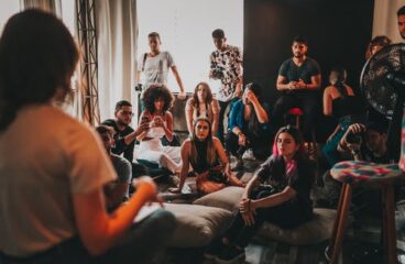 person speaking to a group of people who are sitting and standing